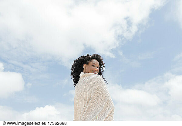 Smiling woman wrapped in towel on sunny day