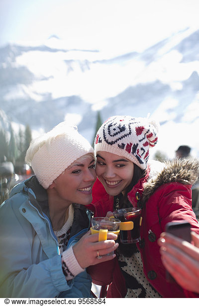 Smiling women in warm clothing drinking tea outdoors