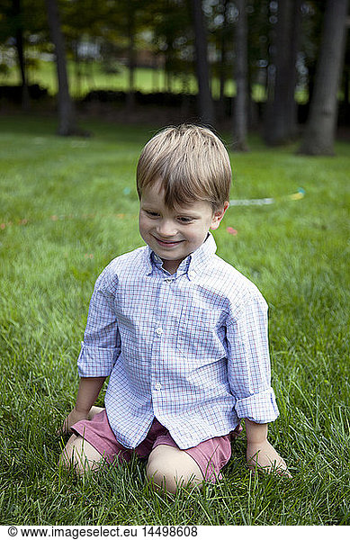 Smiling Young Boy Kneeling in Grass