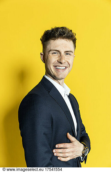Smiling young businessman at yellow background