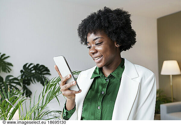 Smiling young businesswoman using smart phone at office