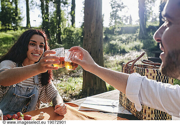 Smiling young couple toasting drinks in forest