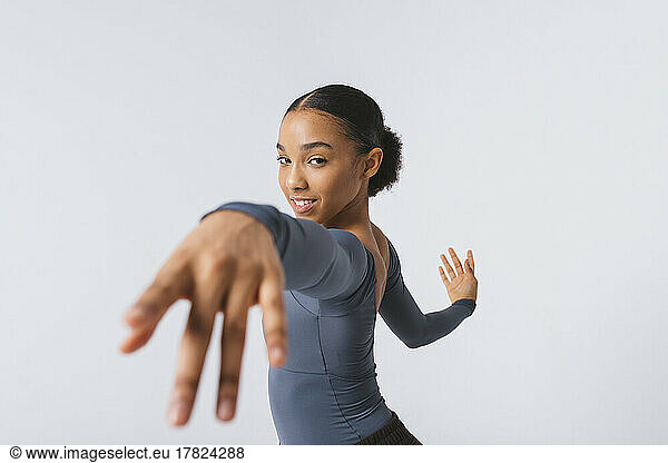 Smiling young dancer practicing ballet against white background
