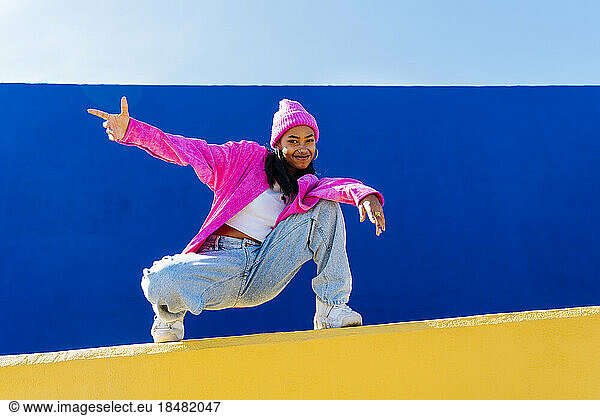 Smiling young dancer sitting on wall