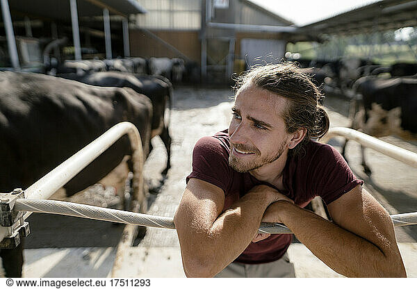 Smiling young farmer at cow house on a farm