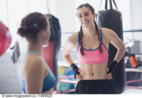 Smiling young female boxers resting in gym