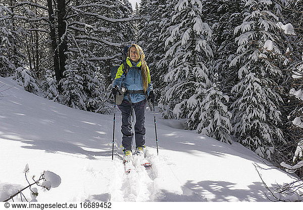Smiling young female hiker splitboarding on snow covered mountain
