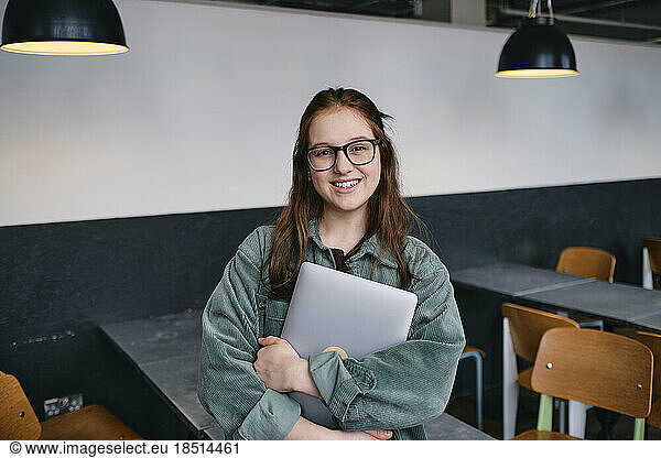 Smiling young freelancer standing in cafe