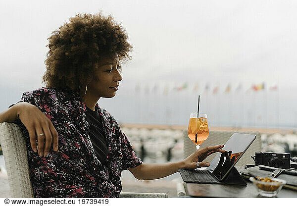 Smiling young freelancer touching and using tablet PC at table