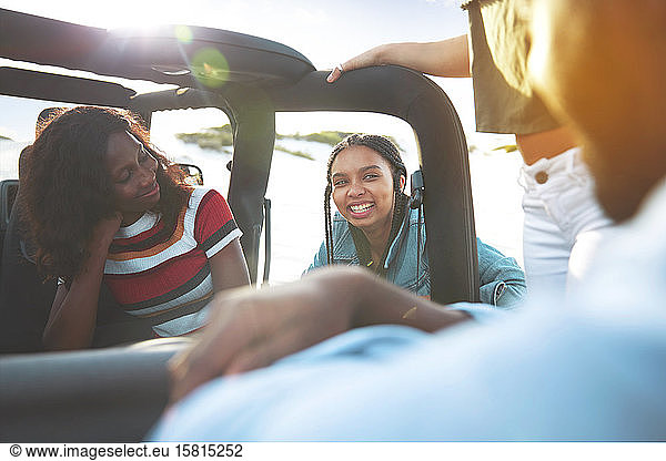 Smiling young friends talking  enjoying road trip in jeep