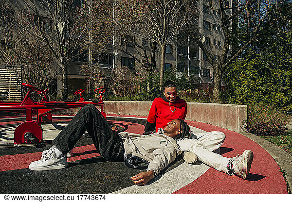 Smiling young male friends spending leisure time in playground on sunny day