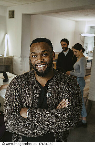 Smiling young male professional with arms crossed in creative office