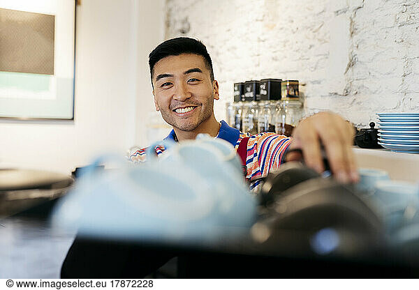 Smiling young man working in coffee shop