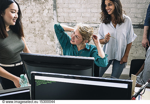 Smiling young multi-ethnic female hackers discussing in creative office