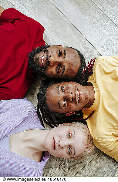 Smiling young multiracial friends lying on floor at home