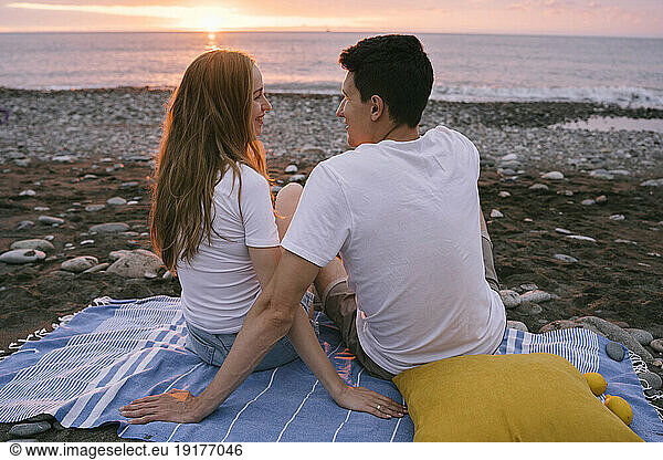 Smiling young romantic couple talking at beach on vacation