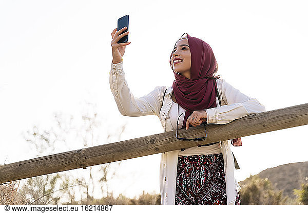 Smiling young tourist woman wearing Hijab taking a selfie