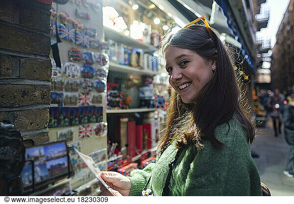 Smiling young woman buying souvenirs at store
