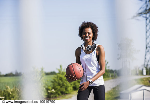 Smiling young woman holding basketball
