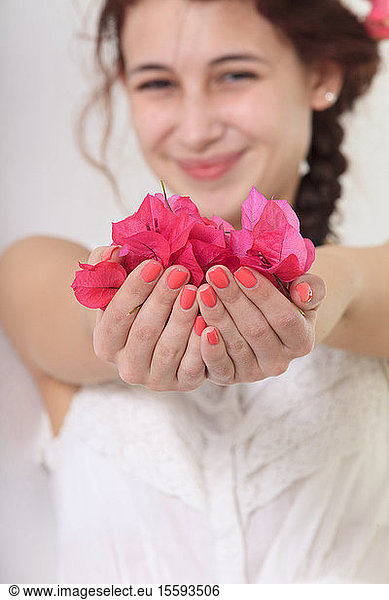 Smiling young woman holding flower petals in her hands