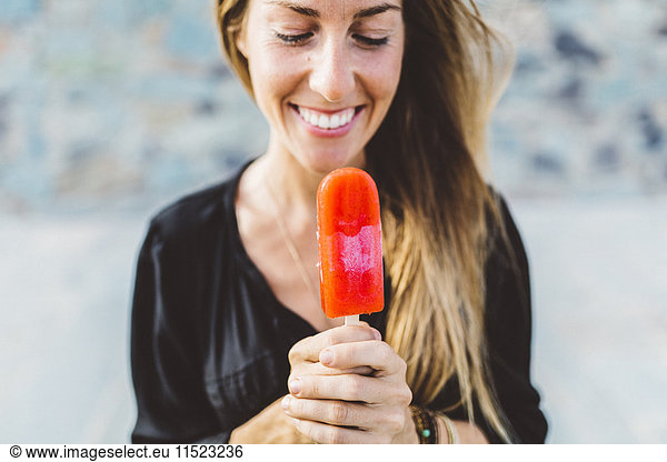 Smiling young woman holding popsicle