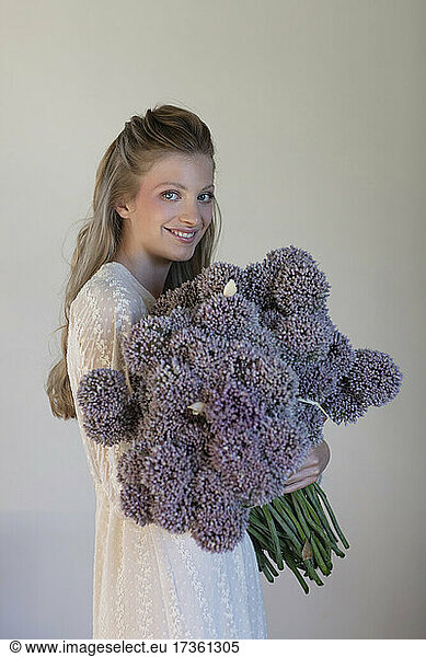 Smiling young woman holding purple allium flowers