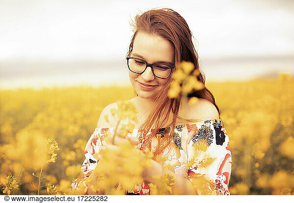 Smiling young woman in a rape field