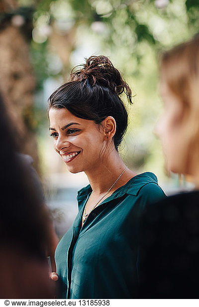 Smiling young woman in balcony with friends during garden party