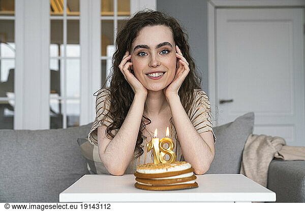 Smiling young woman in front of birthday cake at home