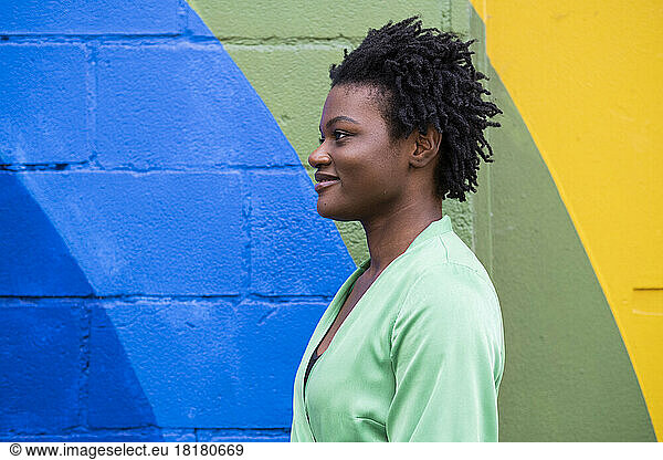 Smiling young woman in front of colorful wall