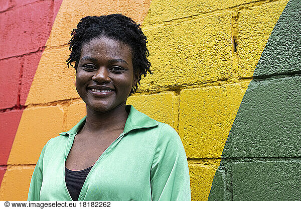 Smiling young woman in front of colorful wall