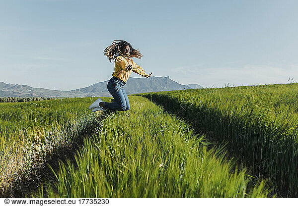 Smiling young woman jumping on green grass