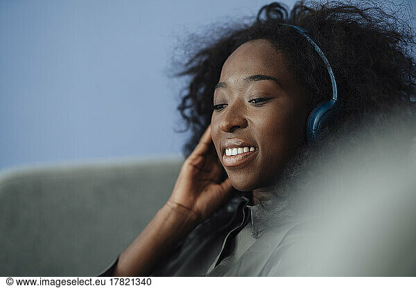 Smiling young woman listening music through wireless headphones
