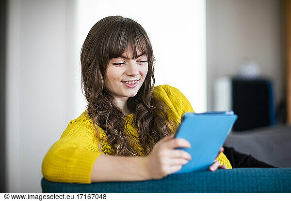 Smiling young woman looking at diary while sitting at home