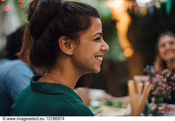 Smiling young woman looking away during dinner party in backyard