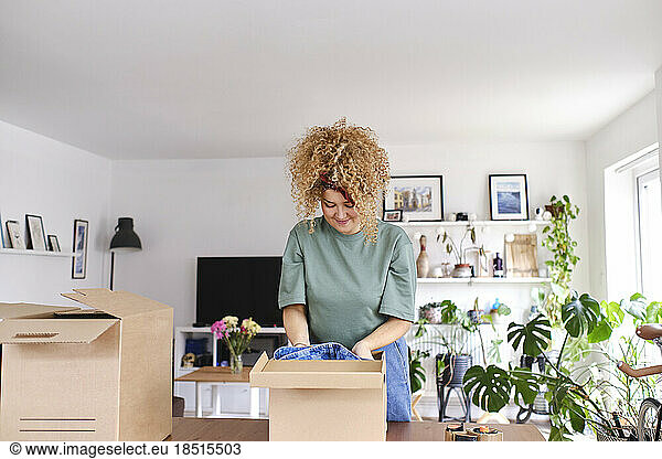 Smiling young woman packing order at home