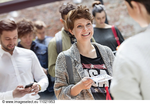 Smiling young woman showing credentials at technology conference