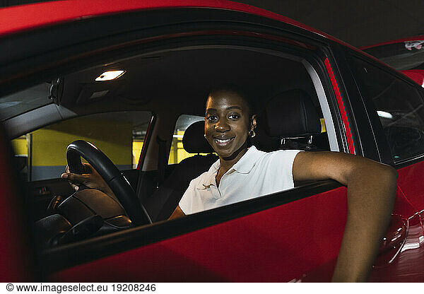 Smiling young woman sitting in car