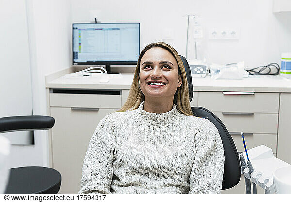 Smiling young woman sitting on dentist chair at clinic