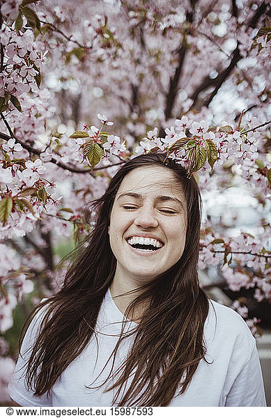 Smiling young woman standing against pink tree