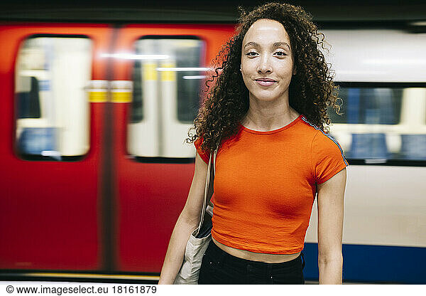 Smiling young woman standing in front of moving train