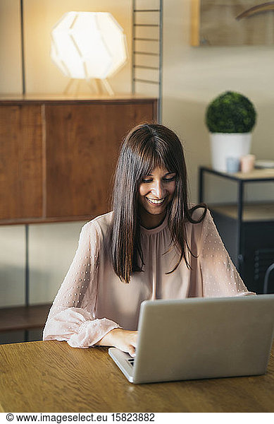 Smiling young woman using laptop at home