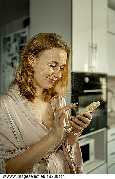 Smiling young woman using smart phone at home
