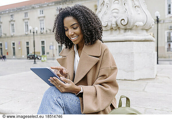 Smiling young woman using tablet PC at town square