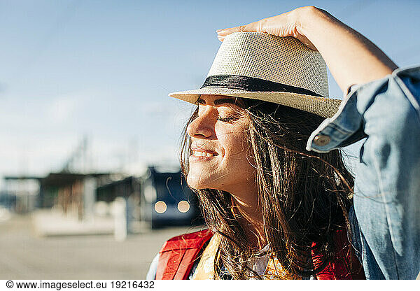 Smiling young woman wearing hat with eyes closed on sunny day