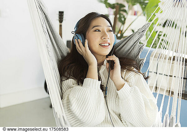 Smiling young woman wearing headphones in hammock