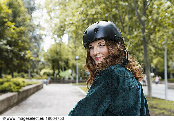 Smiling young woman wearing helmet in park