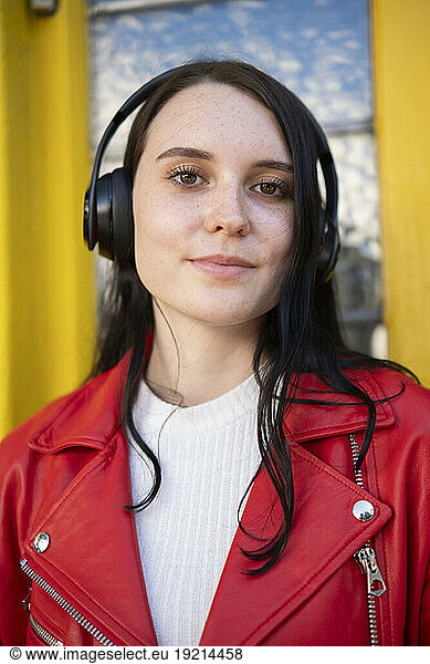 Smiling young woman wearing wireless headphones