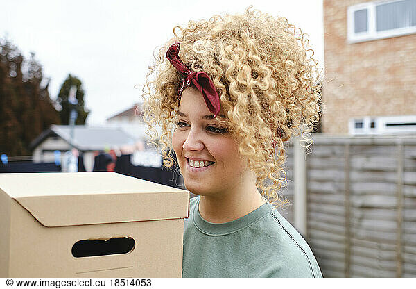 Smiling young woman with cardboard box