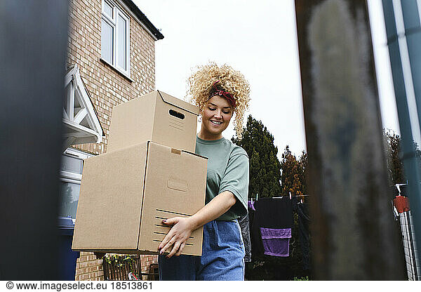 Smiling young woman with curly hair delivering packages